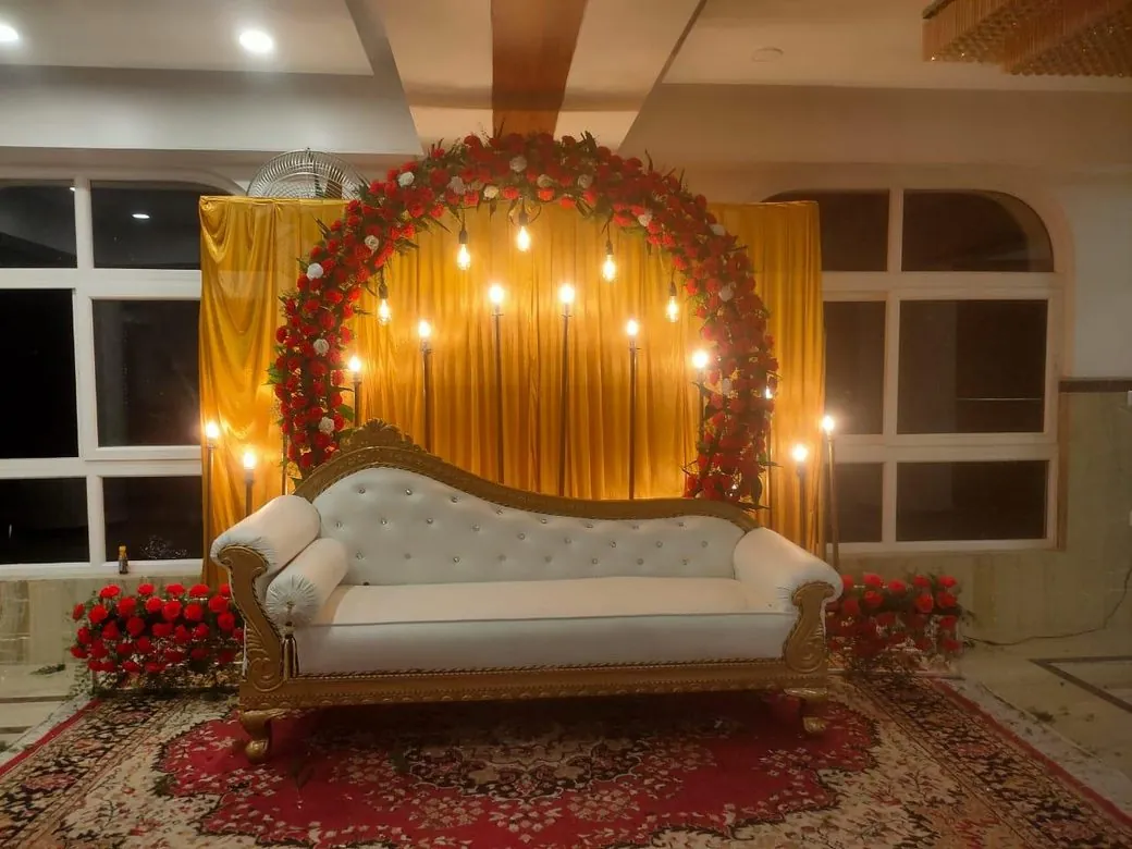 Stage decoration with a red floral arch and warm lights
